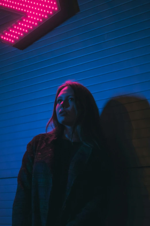 a person is standing in the dark near a neon sign