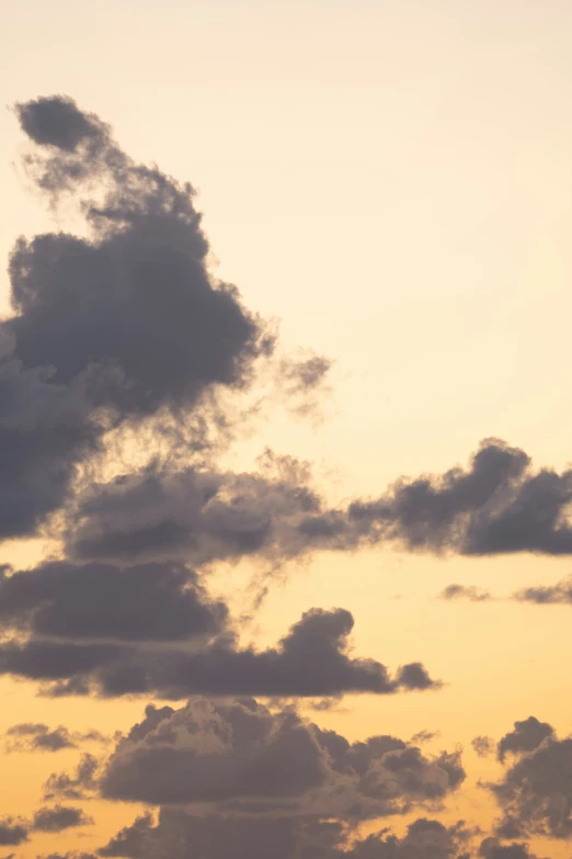 a plane flies in the sky during a cloudy sunrise