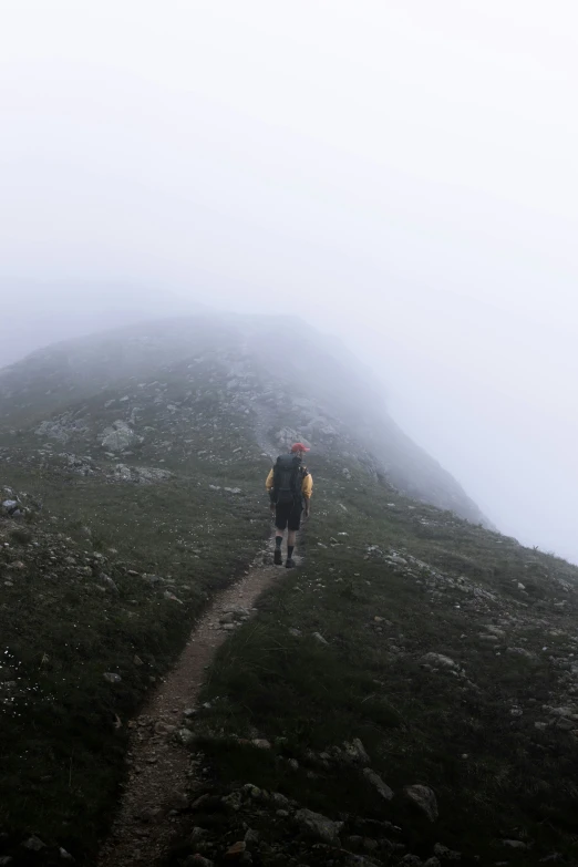 a man in yellow jacket walking up a mountain