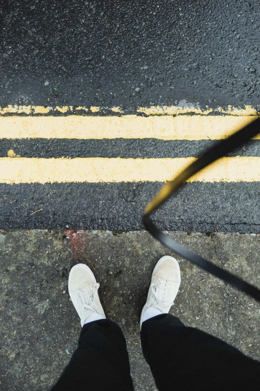 a person wearing white shoes is walking down a road