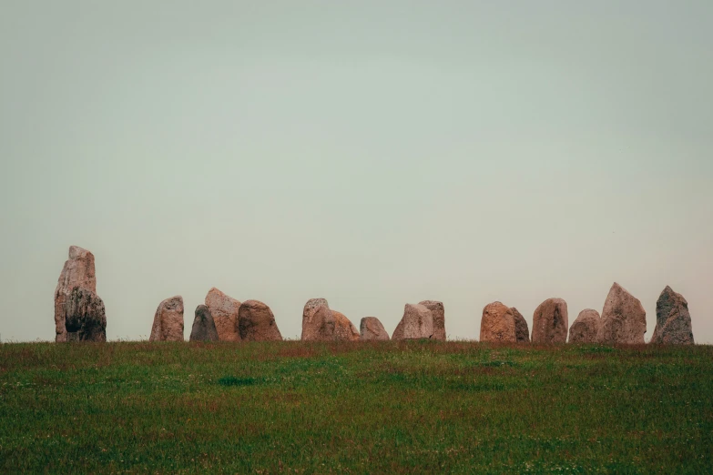 some large stones standing in a row on the grass