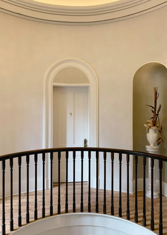 a foyer features a black handrail and a large pot on the pedestal