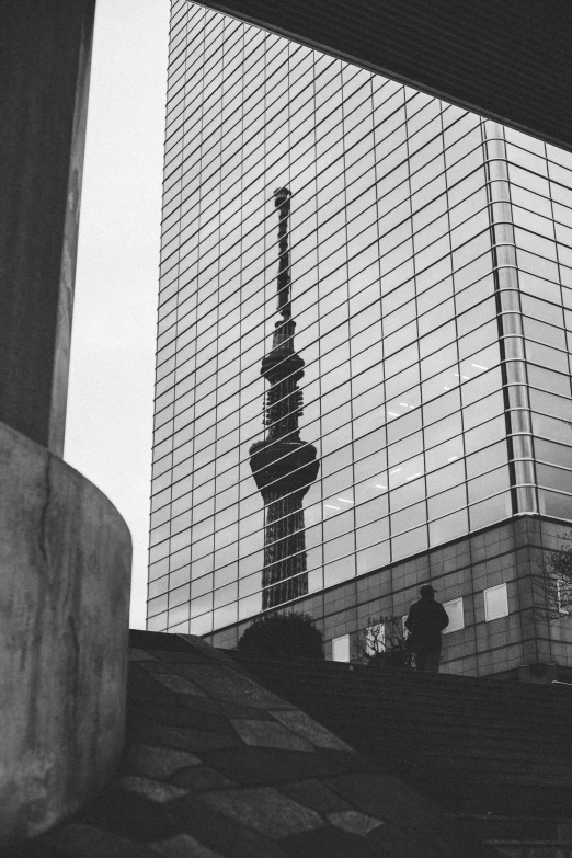 an artistic picture of an outdoor structure reflecting a building with a spire