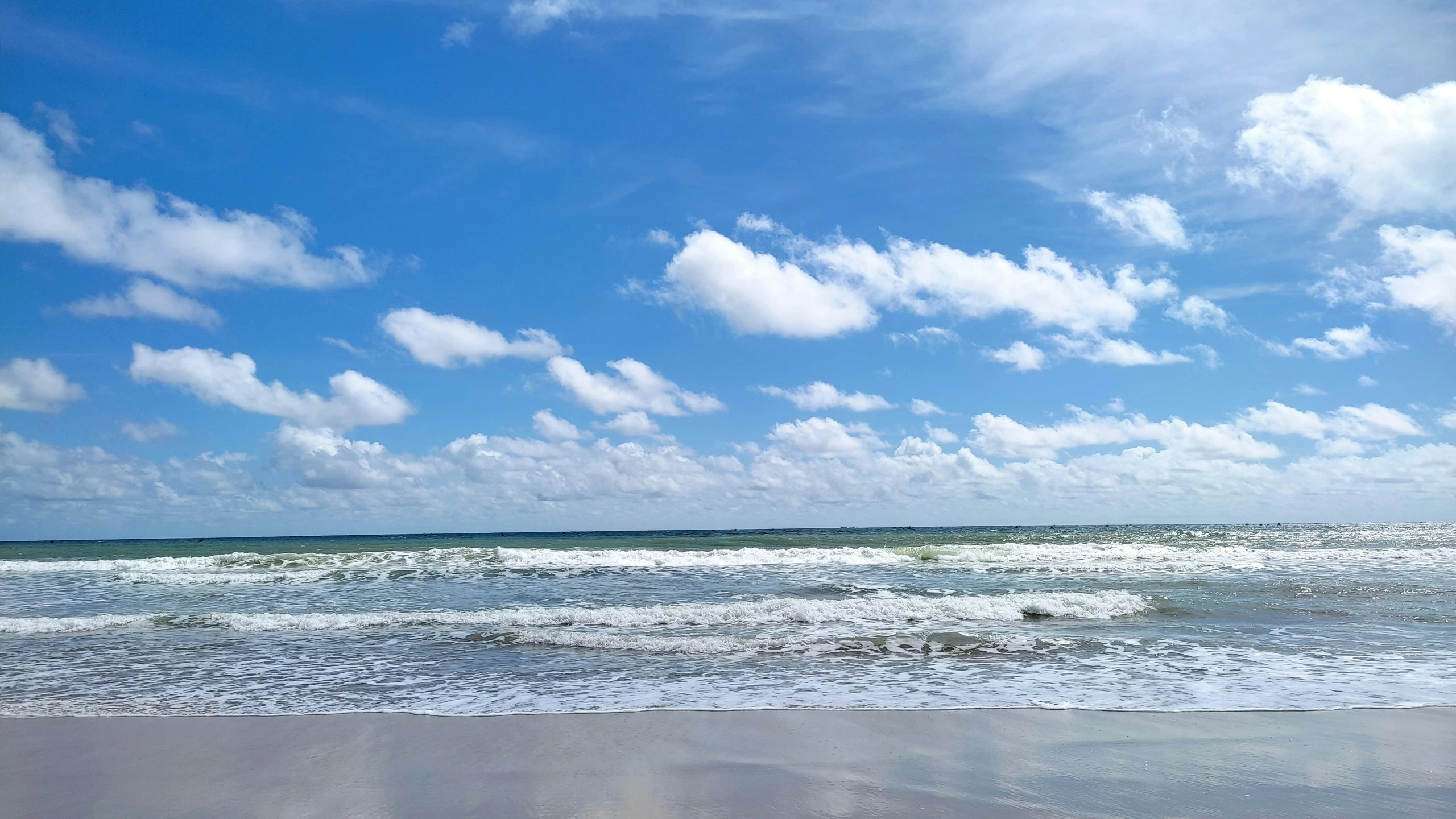 a person walks on the beach while waves roll in