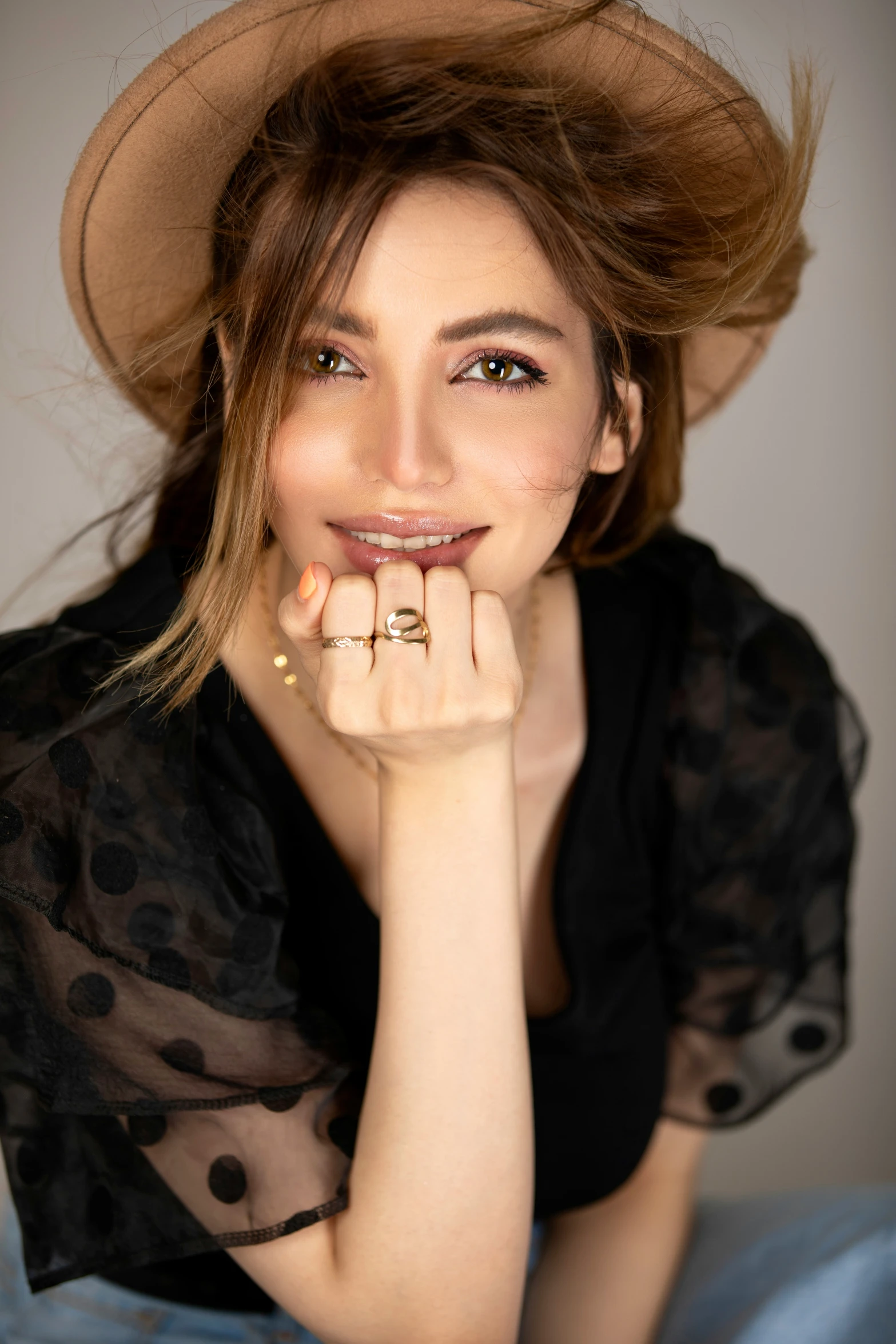 a young woman sitting on top of a couch wearing a polka dot blouse and a hat