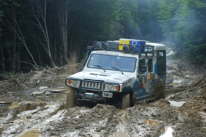 the truck is driving in the mud through the trees