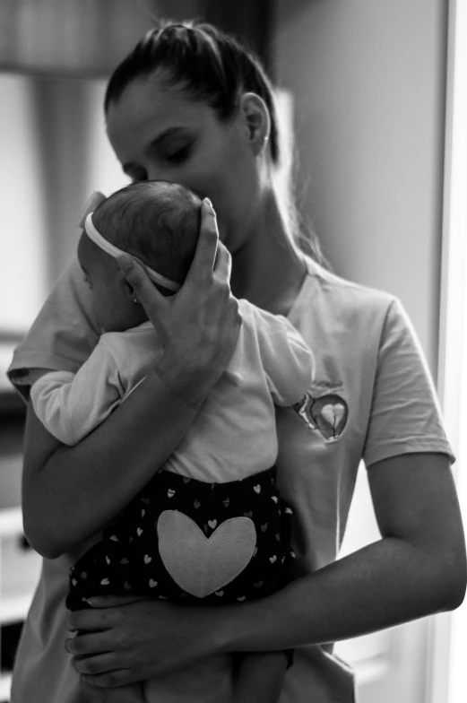 a woman holds a little baby with a heart on it