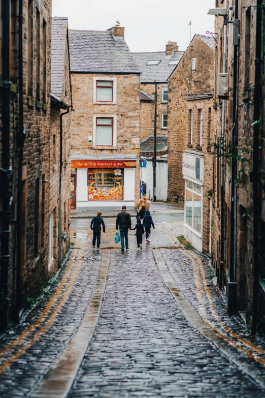 four people walking down an alley way through old buildings