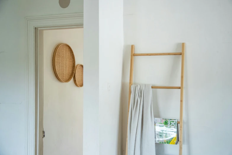 the bathroom has two towels and a wooden ladder in it