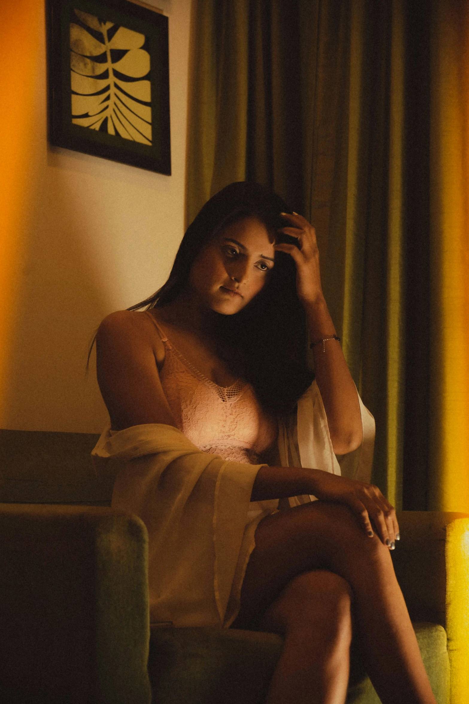 a beautiful woman sitting on top of a couch next to a window