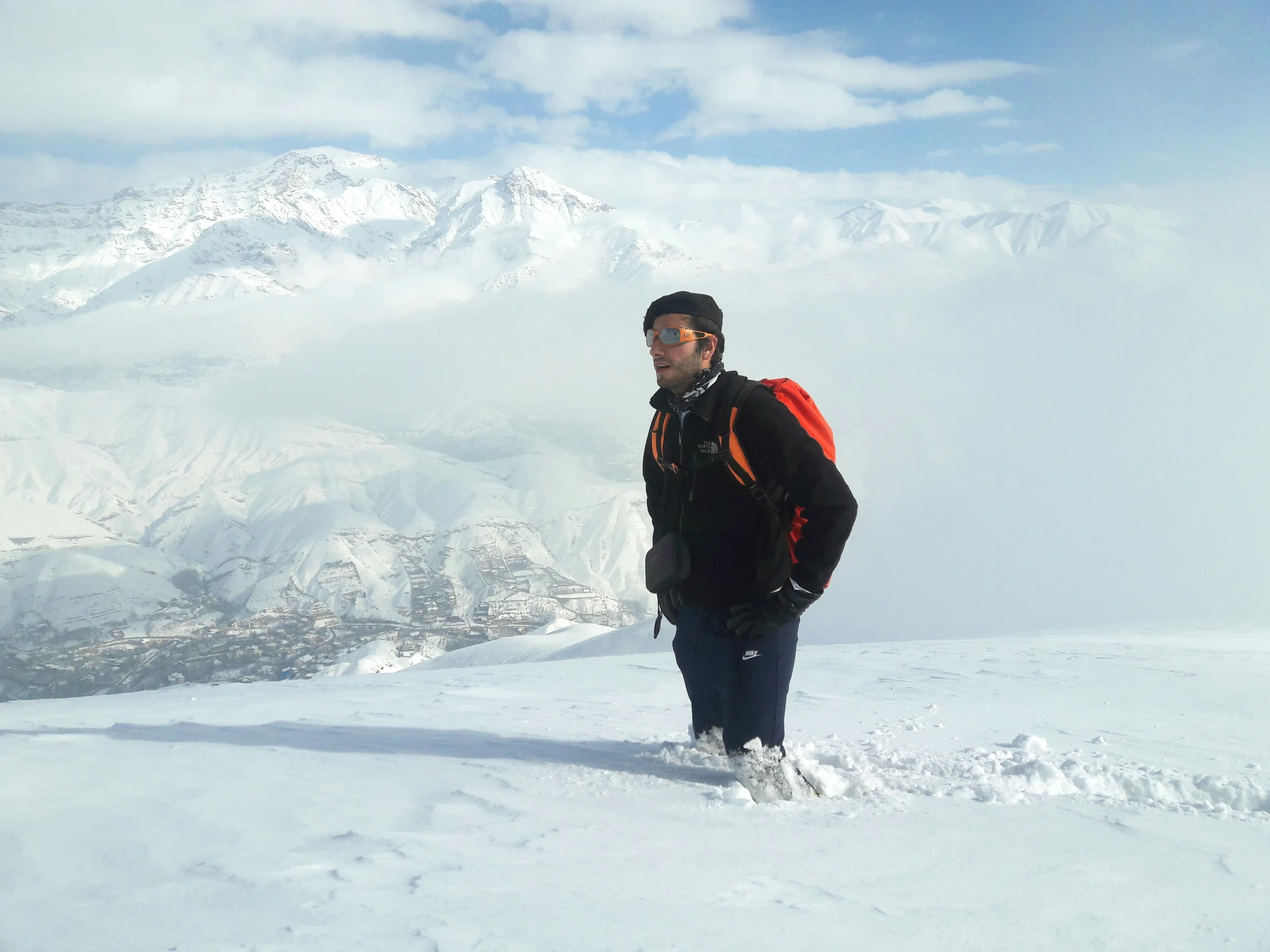 a man standing in the snow on top of a snow covered slope