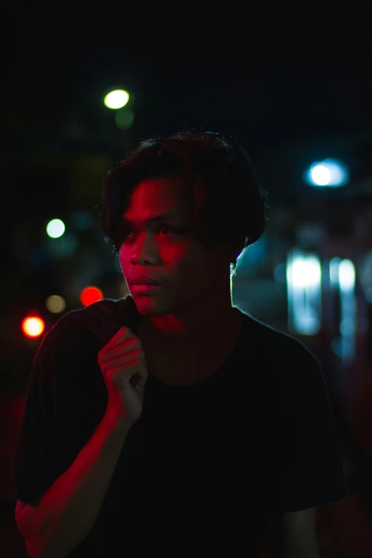 a young man standing in a dark street at night