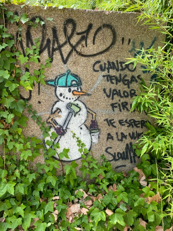 graffiti on concrete near trees and vegetation, with a snowman