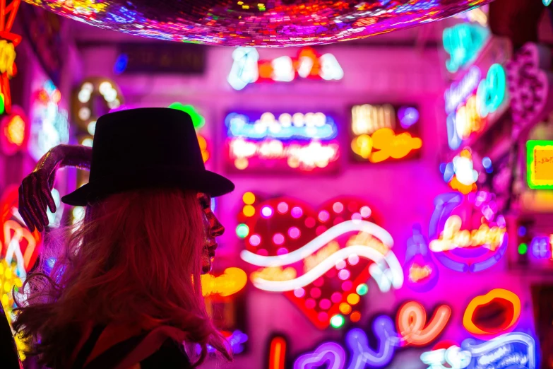 woman in a black top with lighted display of neon signs
