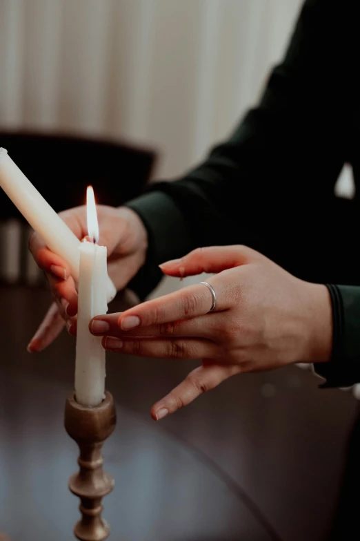 two people sitting at a table holding two candles