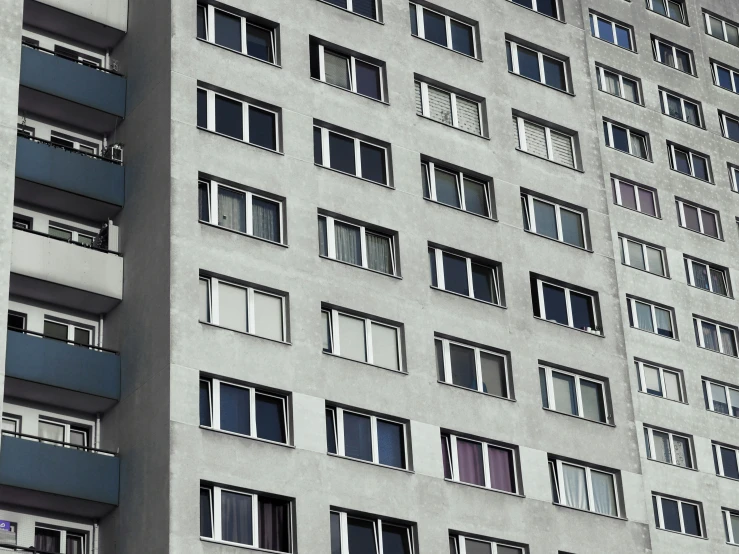 large grey building with three balconies with windows