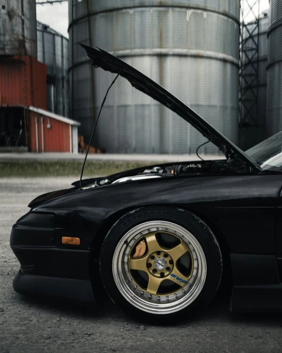 a black car with its hood up parked in front of a silo