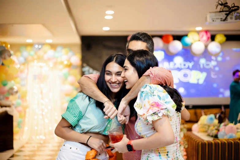 two ladies hugging while they have an over - sized video screen behind them