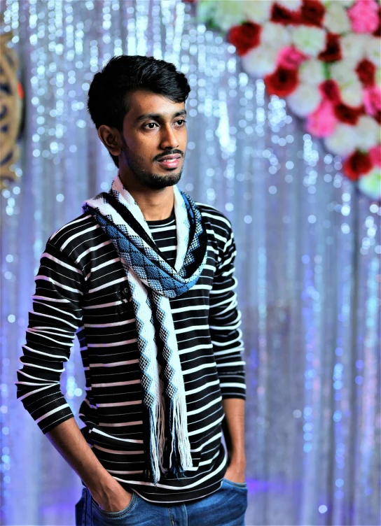 a man wearing a striped sweater stands in front of a floral backdrop