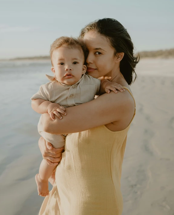 a woman holding a baby on the beach