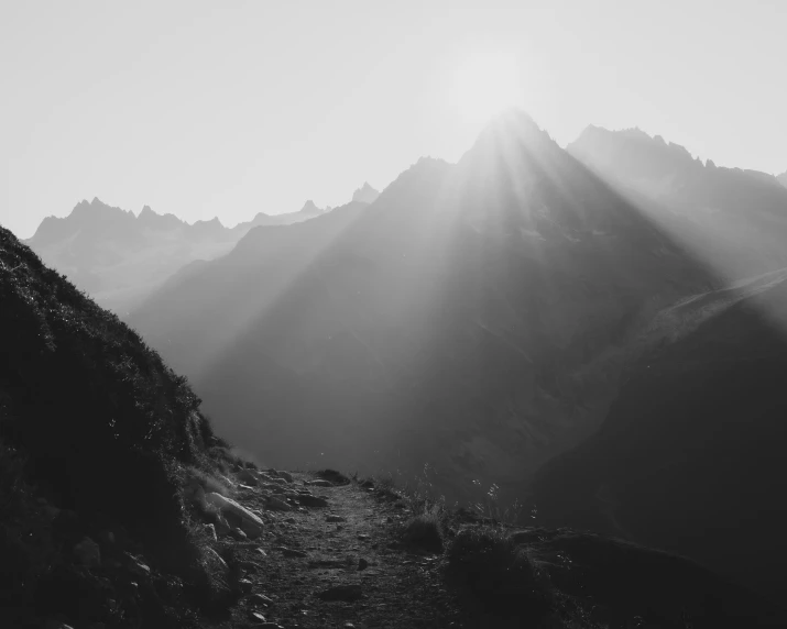 a black and white po of the sun behind some mountains