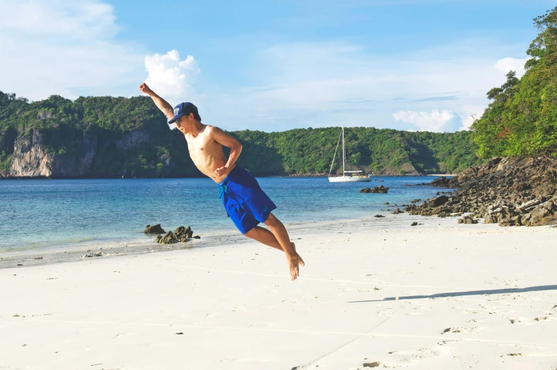 a shirtless man with a frisbee in the air on a beach