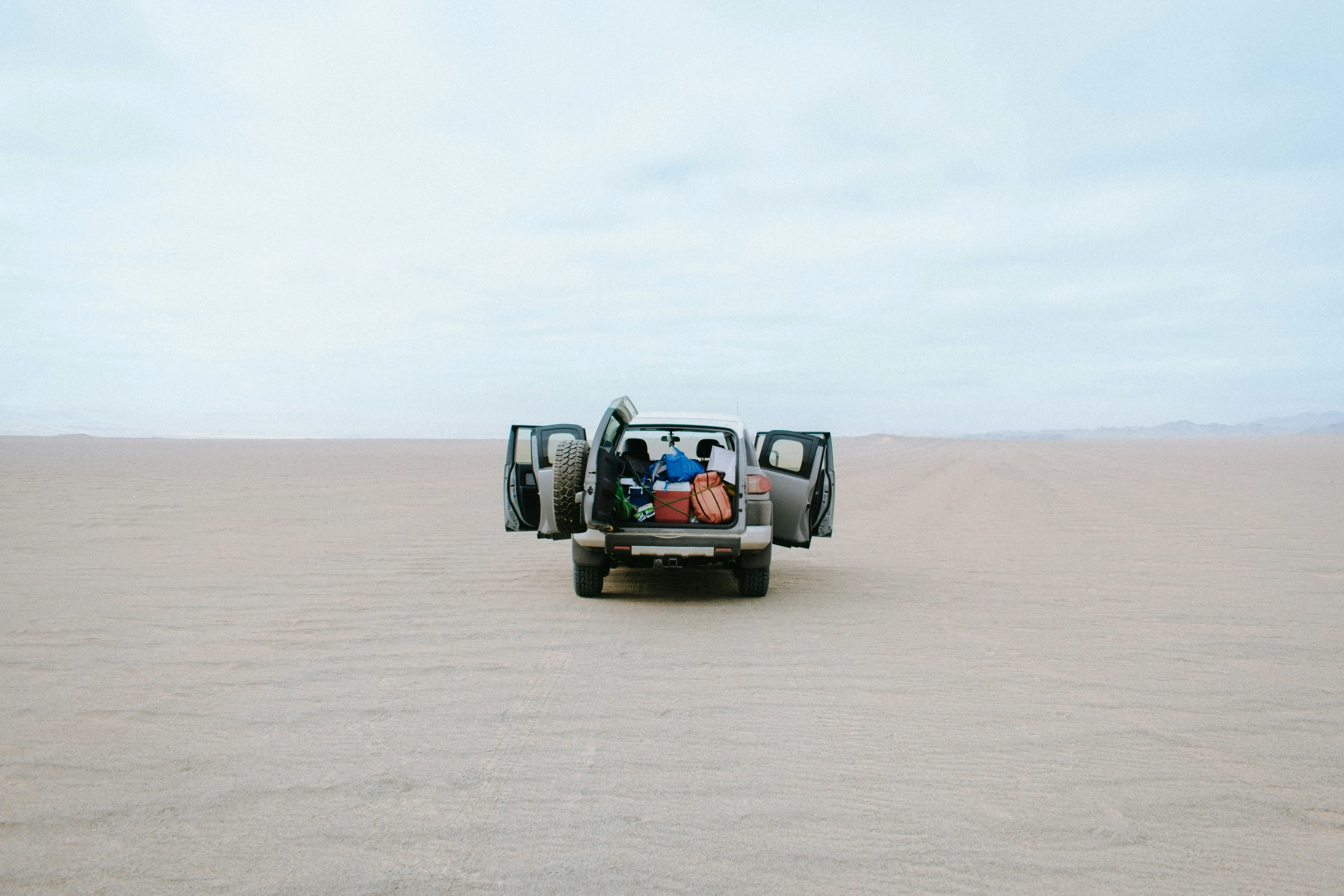 a person sits in the back of a car in the middle of the desert