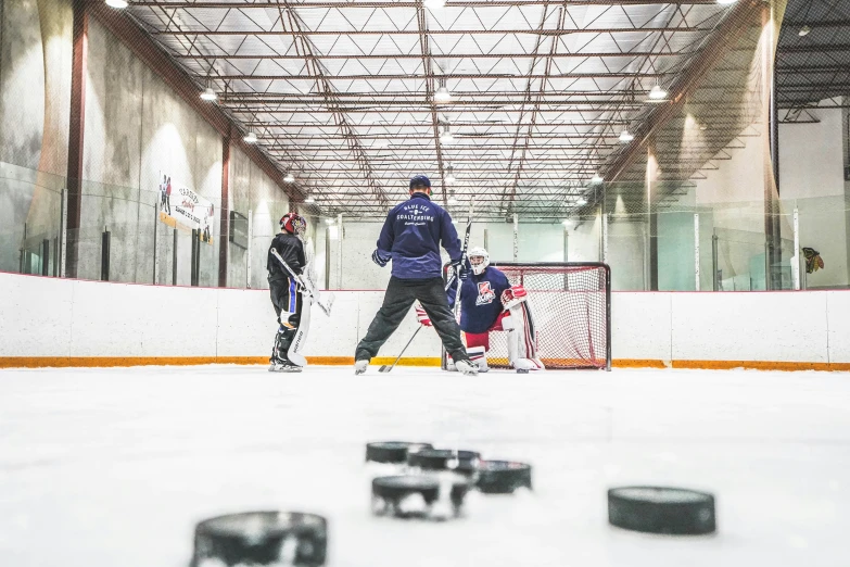 three men playing hockey in a big room