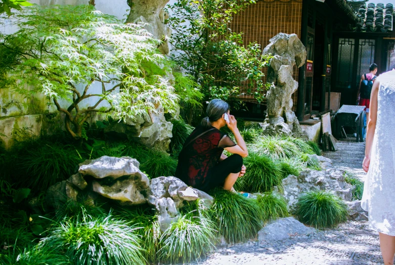 a woman takes a po of a man in a traditional garden