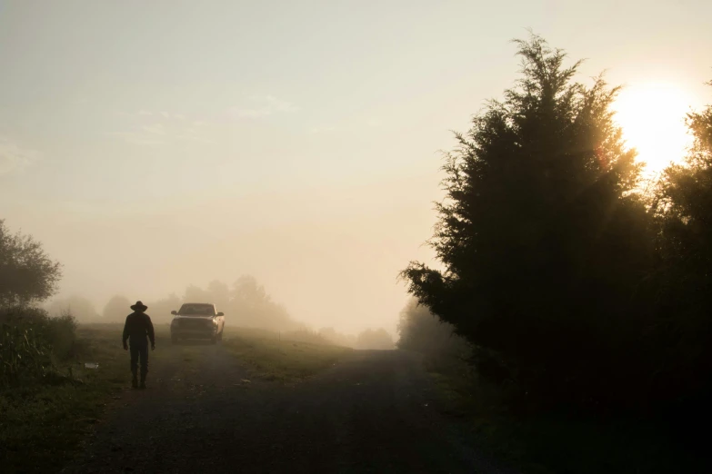 a lone man walking down the road, towards a white pickup truck