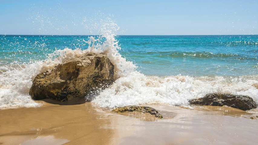 a rock laying on top of a sandy beach near the ocean