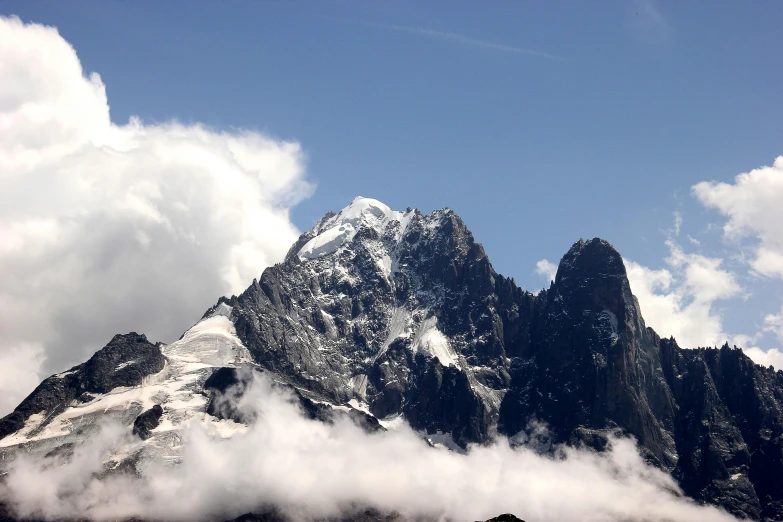 a group of mountains are standing tall with clouds