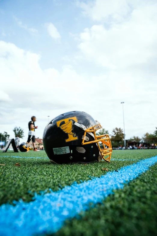 a football helmet sits on the sideline while people walk around behind it