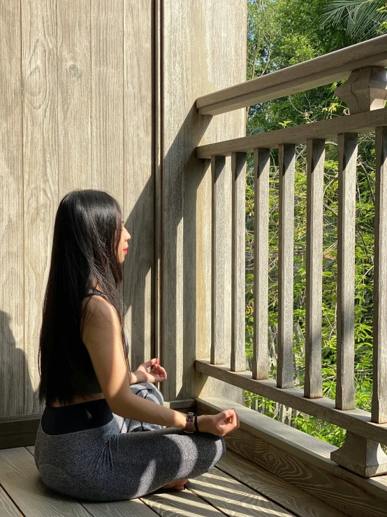 a woman is sitting on a porch by a balcony