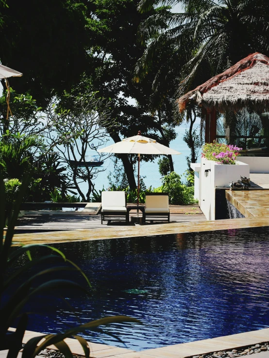 a pool is shown in the shade with two lounge chairs and an umbrella