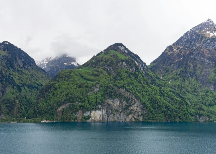 several mountains, one in the distance, are seen behind water