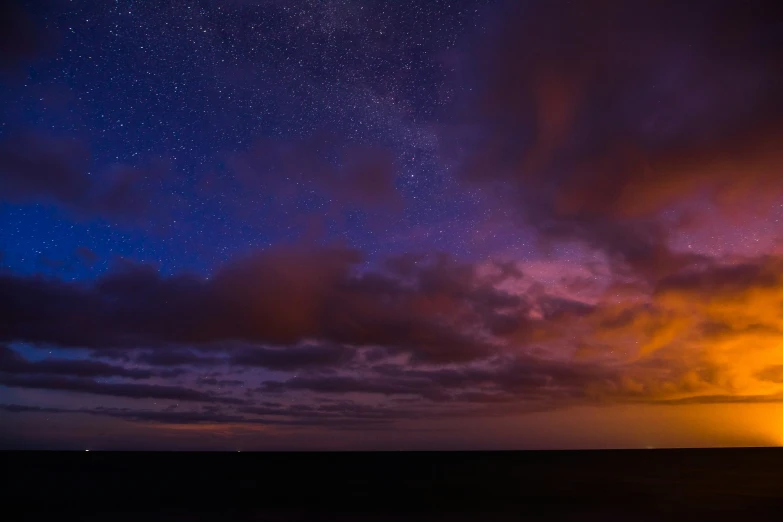 the stars shine brightly on the night sky as seen by a man on a beach