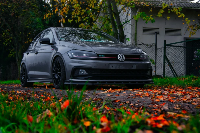 a grey car parked near a tree and fence