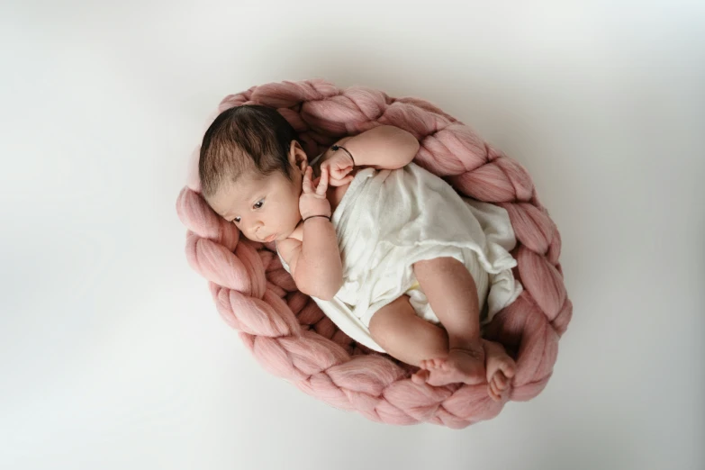 the baby sleeps in pink yarn on white backdrop