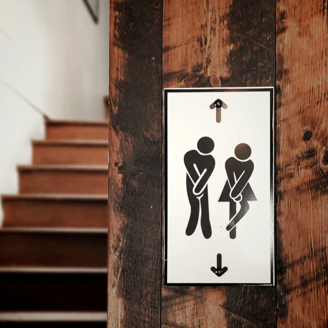 a sign on wooden stairs stating to use the toilet