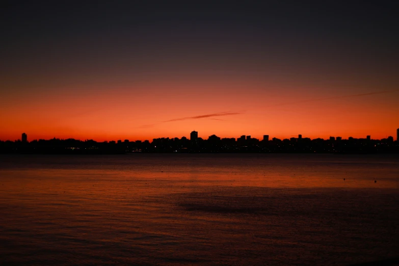 cityscape at sunset overlooking large body of water with boats in the foreground