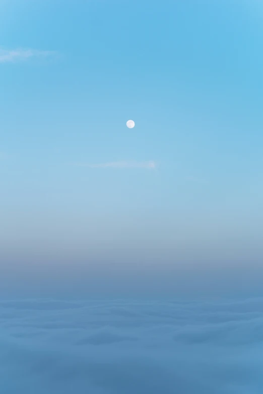 a blue ocean under a clear sky with the moon