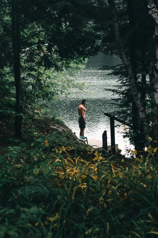 a man in shorts standing at the edge of a lake