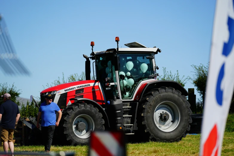 red tractor with large wheels parked in the grass