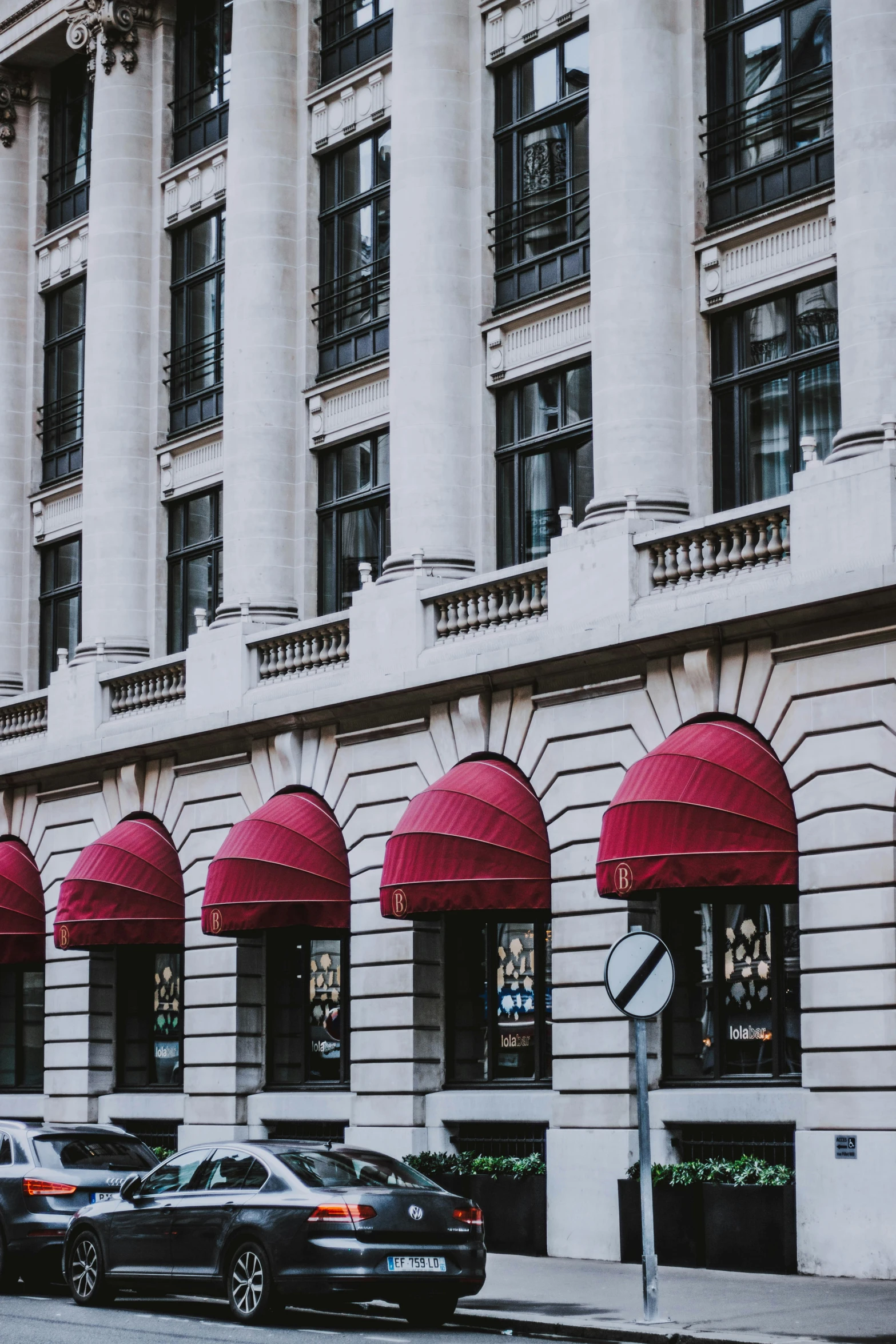 a large white building with red awnings and cars parked outside