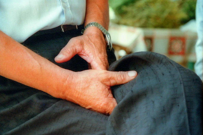 the man is sitting down using his wrist to hold the back