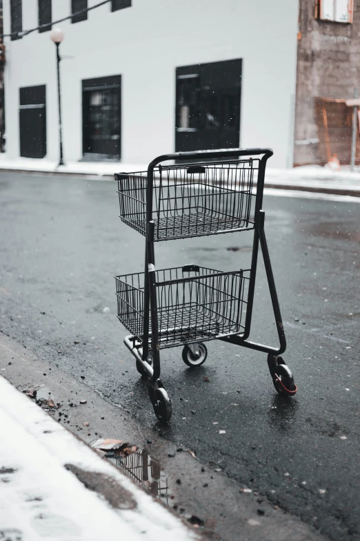 a shopping cart on the side of a street covered in snow