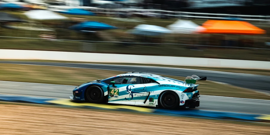 a blue and white sports car driving down the track