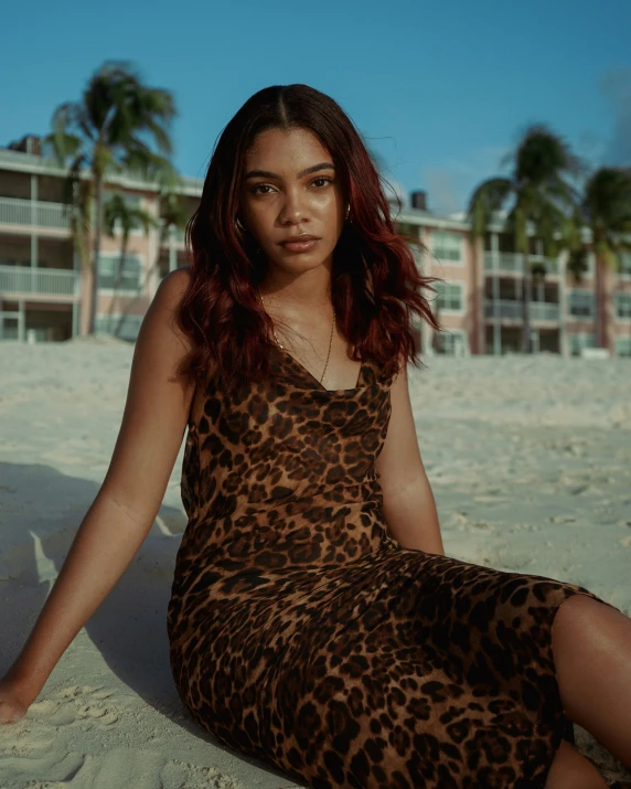 a young woman sits on the beach on a sunny day