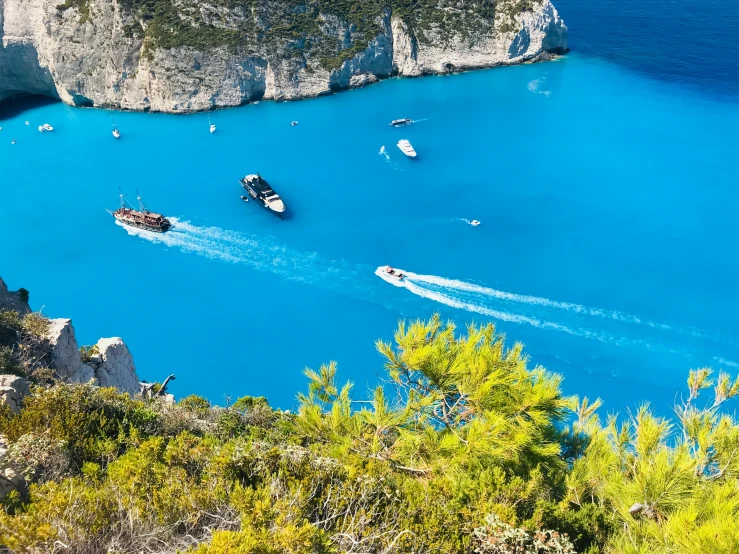 a group of boats driving in a body of blue water
